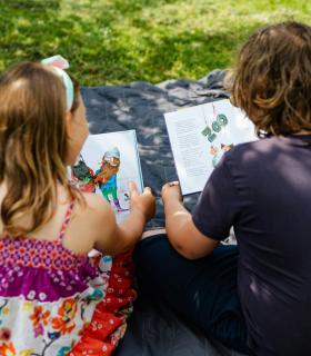 Enfants de dos qui lisent sur l'herbe